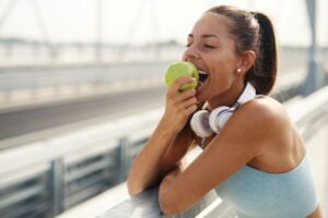 Woman in workout clothes eating an apple 