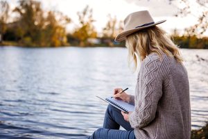 Woman writing in her journal while sitting outdoors